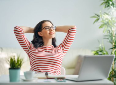 Evde dizüstü bilgisayarda çalışan mutlu ve güzel bir kadın..