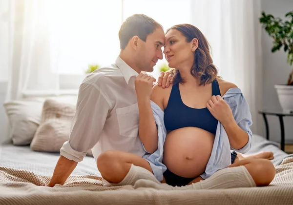 幸せな妊娠中の女性と彼女のハンサムな夫は ベッドで一緒に時間を費やしています 家族が待っている赤ちゃんです — ストック写真