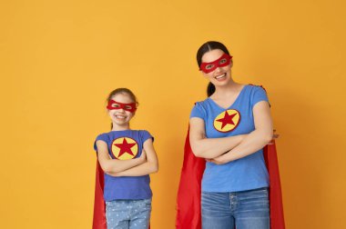 Anne ve çocuğu birlikte oynama. Kız ve anne süper kahraman kostümleri. Annem ve eğleniyor ve gülen çocuk. Aile tatili ve beraberlik.