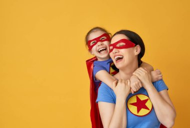 Anne ve çocuğu birlikte oynama. Kız ve anne süper kahraman kostümleri. Annem ve eğleniyor ve gülen çocuk. Aile tatili ve beraberlik.