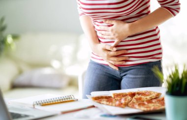 İş yerinde masaya pizza yemek ve mide sorunları kadın.