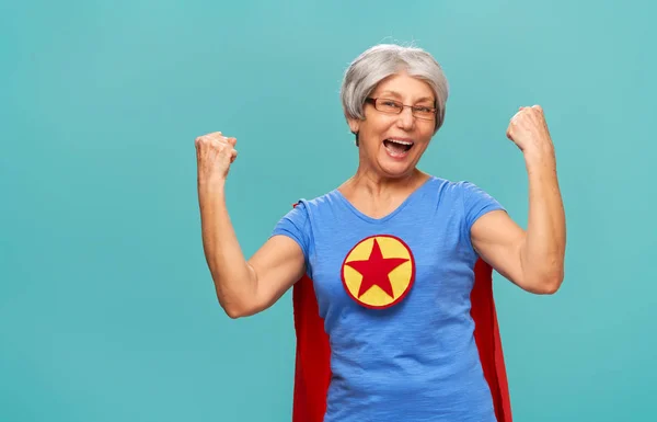 Радостная Красивая Пожилая Женщина Костюме Супергероя Позирует Бирюзовом Фоне — стоковое фото