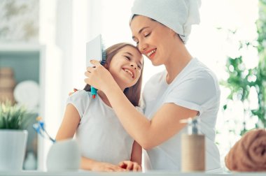 Mutlu bir aile! Anne ve kızı kız çocuk saç banyoda penye.