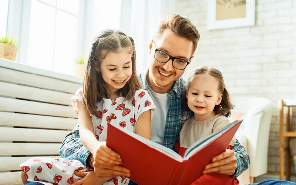 Отец читает книгу своим дочерям — стоковое фото