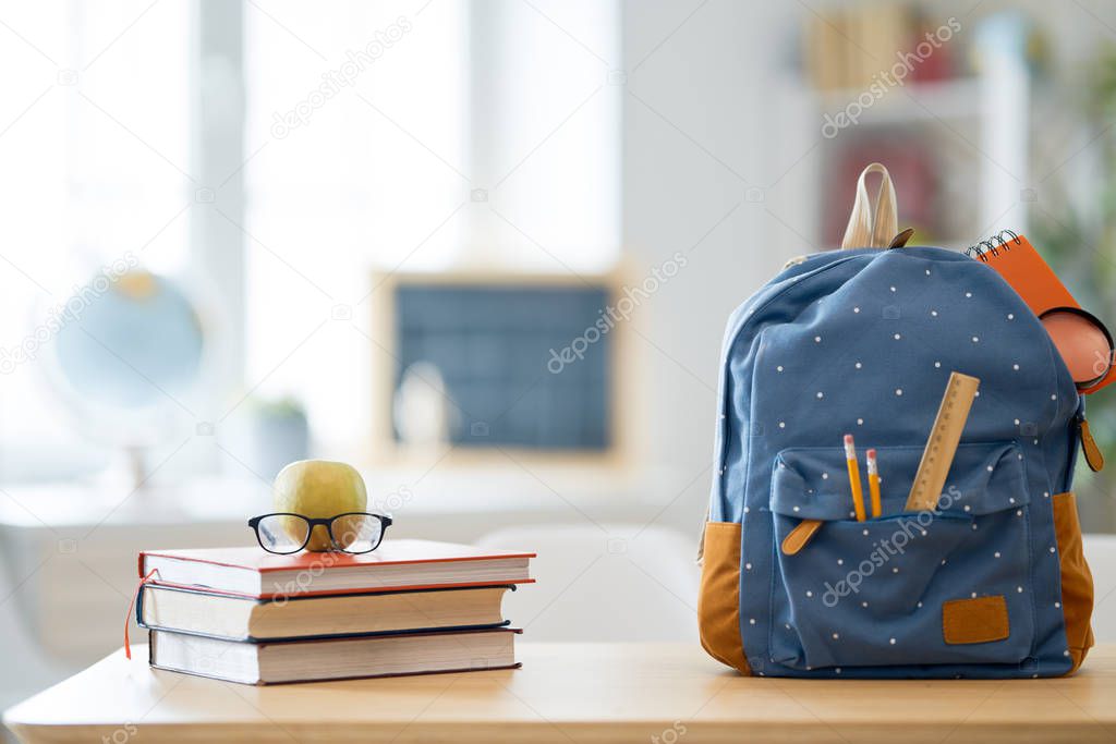 Apple, pile of books and backpack