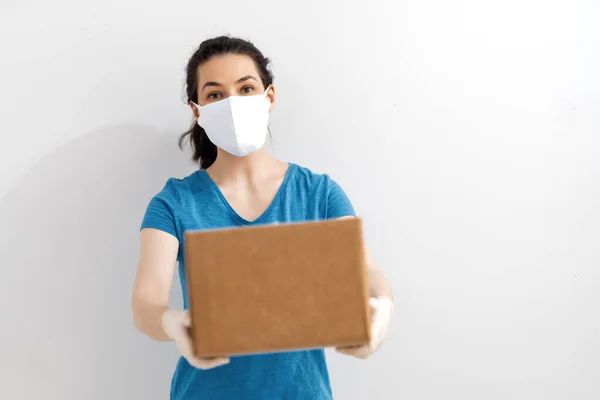 送货妇女手持纸板箱 戴着医用橡胶手套和面罩 网上购物 — 图库照片