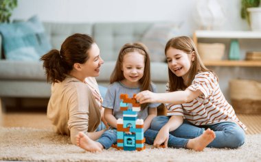 Mutlu bir gün! Anne ve kızları oynuyorlar, gülüyorlar ve sarılıyorlar. Aile tatili ve birliktelik. 
