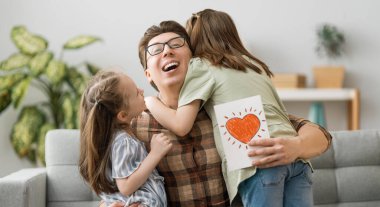 Babalar günün kutlu olsun! Çocukların kızları babalarını tebrik ediyor ve ona kartpostal veriyorlar. Baba ve kızlar gülümsüyor ve sarılıyorlar. Aile tatili ve birliktelik.