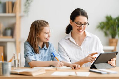 Okula dönelim. Mutlu çocuk ve yetişkin masada oturuyor. Ödev yapan ya da online eğitim alan kız.