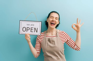 Küçük işletme sahibi gülümsüyor ve karantinadan sonra covid-19 nedeniyle dükkanın yeniden açılacağı tabelasını tutuyor..