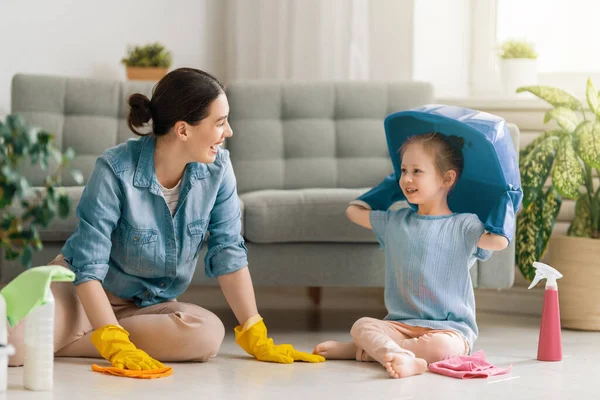 快乐的家庭在家里妈妈和女儿在屋里打扫卫生 一个年轻的女人和一个小女孩在擦拭灰尘 可爱的小助手 — 图库照片