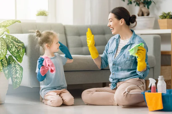 家庭で幸せな家族 母親と娘は家で掃除をしている 若い女性と子供の女の子がほこりをかぶっている かわいいヘルパーさん — ストック写真