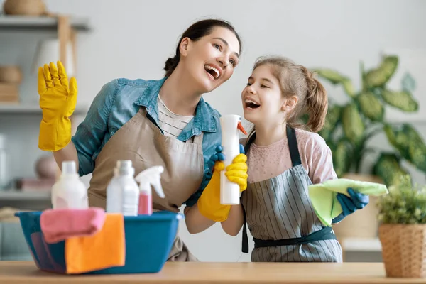 快乐的家庭在家里妈妈和女儿在屋里打扫卫生 一个年轻的女人和一个小女孩在擦拭灰尘 可爱的小助手 — 图库照片