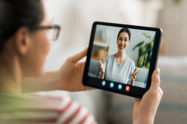 Genç kadın arkadaşlarıyla uzaktan konuşmak için tablet bilgisayar kullanıyor. Komik kız evde kalıp eğleniyor..