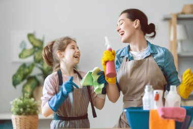 Evde mutlu bir aile. Anne ve kızı evde temizlik yapıyor. Genç bir kadın ve kız toz alıyorlar. Sevimli küçük yardımcı..