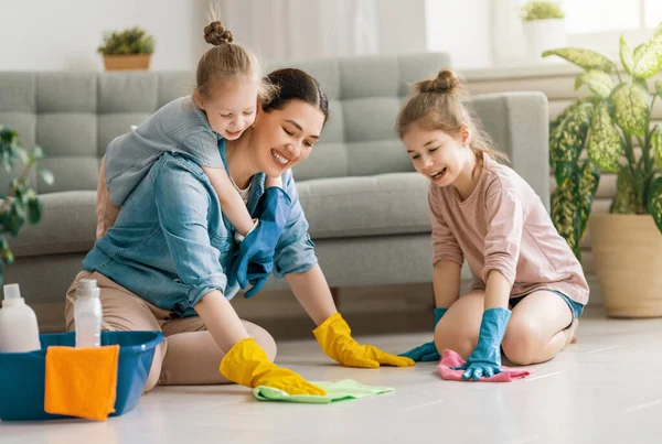 家庭で幸せな家族 母親と娘は家の掃除をしている 若い女性と子供の女の子がほこりをかぶっている かわいいヘルパーさん — ストック写真
