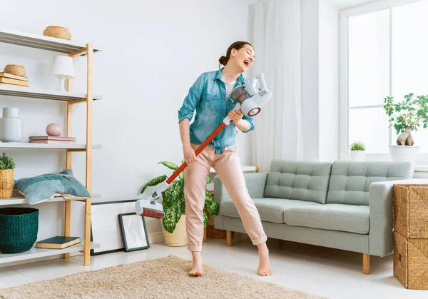 Happy woman vacuuming the room. Housewife doing the cleaning in the house.