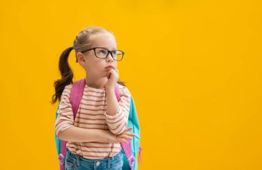 Okula dön ve mutlu ol! Renkli duvar arka planında sevimli, çalışkan bir çocuk. Sırt çantalı çocuk. Kız çalışmaya hazır..