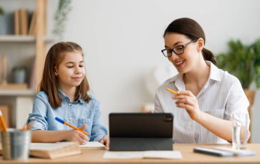 Okula dönelim. Mutlu çocuk ve yetişkin masada oturuyor. Ödev yapan ya da online eğitim alan kız.