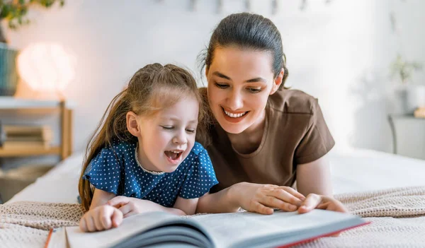 快乐温馨的家庭 漂亮的年轻母亲在家里的床上给女儿读书 — 图库照片