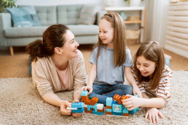 Mutlu bir gün! Anne ve kızları oynuyorlar, gülüyorlar ve sarılıyorlar. Aile tatili ve birliktelik. 
