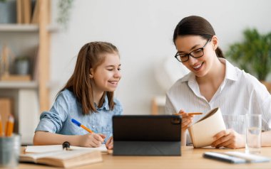 Okula dönelim. Mutlu çocuk ve yetişkin masada oturuyor. Ödev yapan ya da online eğitim alan kız.