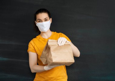 Tıbbi kauçuk eldiven ve maske içinde paketler taşıyan teslimatçı kadın. İnternetten alışveriş. Karantina.
