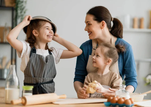 幸せな家族は一緒にパン屋を準備しています 母親と子供の娘はクッキーを調理し キッチンで楽しんでいます 自家製の食べ物と小さなヘルパー — ストック写真