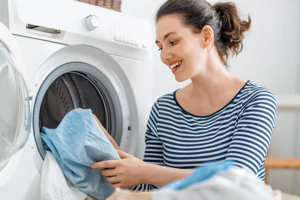 Όμορφη Νεαρή Γυναίκα Χαμογελάει Ενώ Πλένει Ρούχα Στο Σπίτι — Φωτογραφία Αρχείου