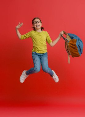 Okula dön ve mutlu ol! Renkli duvar arka planında sevimli, çalışkan bir çocuk. Sırt çantalı çocuk. Kız çalışmaya hazır..