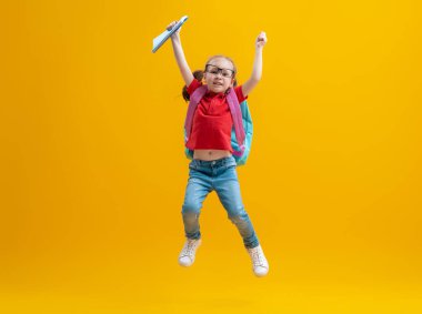 Okula dön ve mutlu ol! Renkli duvar arka planında sevimli, çalışkan bir çocuk. Sırt çantalı çocuk. Kız çalışmaya hazır..