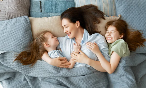 素敵な女の子と彼らの母親は晴れた朝をお楽しみください 自宅で楽しい時間を 子供たちは眠りから覚めます 寝室のベッドで遊ぶ家族 — ストック写真