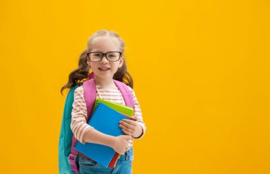 Okula dön ve mutlu ol! Renkli duvar arka planında sevimli, çalışkan bir çocuk. Sırt çantalı çocuk. Kız çalışmaya hazır..