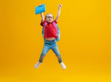 Okula dön ve mutlu ol! Renkli duvar arka planında sevimli, çalışkan bir çocuk. Sırt çantalı çocuk. Kız çalışmaya hazır..