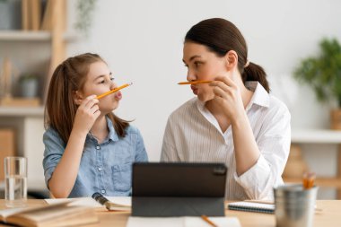 Okula dönelim. Mutlu çocuk ve yetişkin masada oturuyor. Ödev yapan ya da online eğitim alan kız.