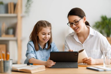 Okula dönelim. Mutlu çocuk ve yetişkin masada oturuyor. Ödev yapan ya da online eğitim alan kız.