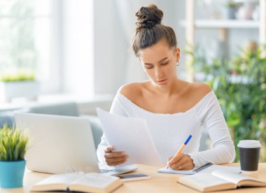 İnternette ders çalışan, Webinar izleyen, dizüstü bilgisayarda podcast yapan notlar alan, çalışma masasında oturan genç bir iş kadını. E-öğrenme kavramı.