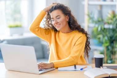 İnternette ders çalışan, Webinar izleyen, dizüstü bilgisayarda podcast yapan notlar alan, çalışma masasında oturan genç bir iş kadını. E-öğrenme kavramı.