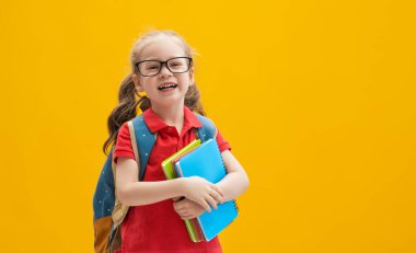 Okula dön ve mutlu ol! Renkli duvar arka planında sevimli, çalışkan bir çocuk. Sırt çantalı çocuk. Kız çalışmaya hazır..