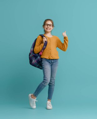 Okula dön ve mutlu ol! Renkli duvar arka planında sevimli, çalışkan bir çocuk. Sırt çantalı çocuk. Kız çalışmaya hazır..