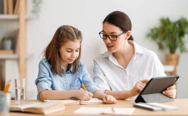 Okula dönelim. Mutlu çocuk ve yetişkin masada oturuyor. Ödev yapan ya da online eğitim alan kız.