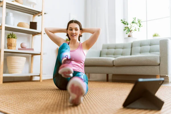 身穿活动服的年轻女子在家锻炼时观看平板电脑在线课程 — 图库照片