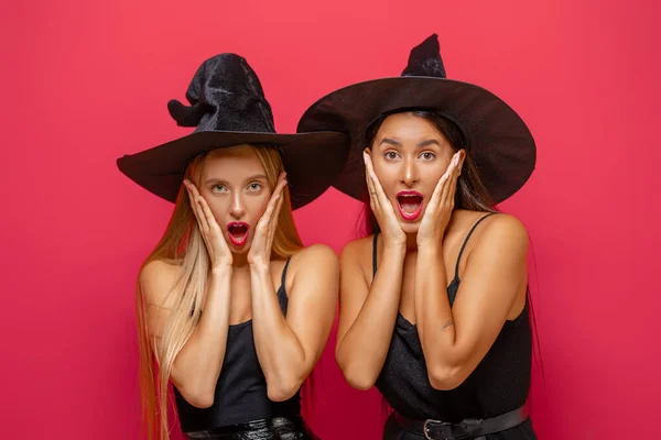 万圣节快乐 两个穿着黑色女巫服装的年轻女人穿着红色背景的派对 — 图库照片