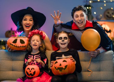 Anne, baba ve çocukları evde eğleniyorlar. Cadılar Bayramı 'nı kutlayan mutlu aile. İnsanlar karnaval kostümü ve makyaj yapıyor..