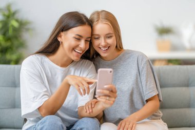 Genç kadınlar telefon kullanıyor. Komik kızlar evde eğleniyor..