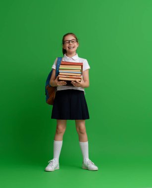 Okula dön ve mutlu ol! Renkli duvar arka planında sevimli, çalışkan bir çocuk. Sırt çantalı çocuk. Kız çalışmaya hazır..