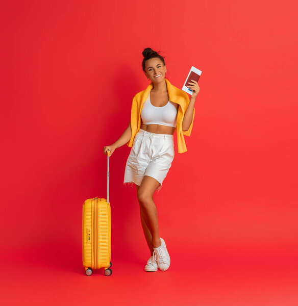Go on an adventure! Happy woman going traveling. Young person with suitcase on color background.