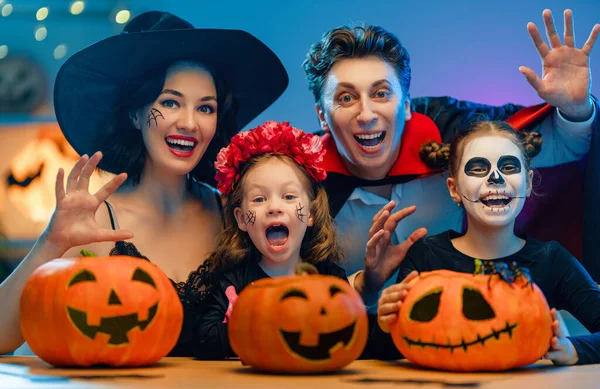 Anne, baba ve çocukları evde eğleniyorlar. Cadılar Bayramı 'nı kutlayan mutlu aile. İnsanlar karnaval kostümü ve makyaj yapıyor..