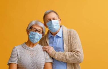 Coronavirus ve grip salgını sırasında yüz maskesi takan yaşlı çift. Virüs ve hastalık koruması, ev karantinası. COVID-2019. Maskeleri çıkarmak ya da çıkarmak.