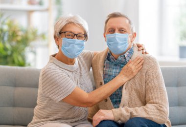 Coronavirus ve grip salgını sırasında maske takan yaşlı bir çift. Virüs ve hastalık koruması, ev karantinası. COVID-2019. Maskeleri çıkarmak ya da çıkarmak.